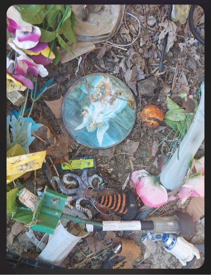 Discarded decorations near a dumpster at Cedar Hill Cemetery, according to cemetery critics.