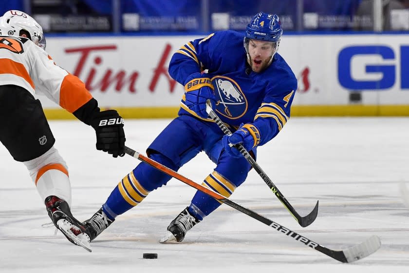 FILE - Buffalo Sabres left wing Taylor Hall (4) passes the puck while pressured by Philadelphia Flyers center Joel Farabee.