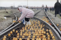 <p>A woman lights a candle on the rail tracks leading to the Nazi concentration camp of Auschwitz-Birkenau, Jan. 27, 1995, during the commemoration of the Soviet liberation of the camp 50 years ago. An estimated 1.5 million people were killed in the camp during Nazi rule. (Photo: Jacqueline Larma/AP) </p>