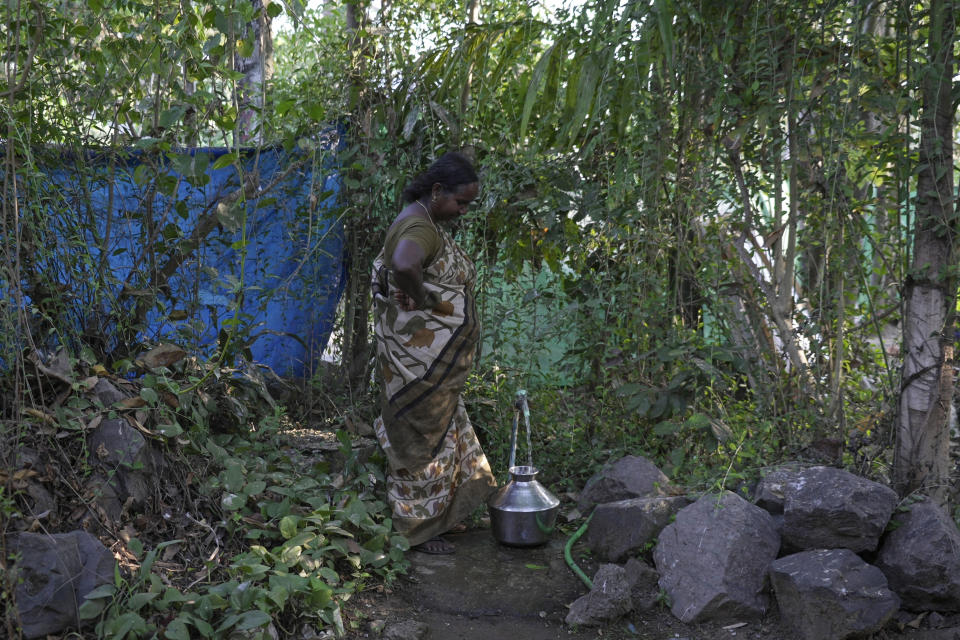 Omana Manikuttan fills a bucket with drinking water she gets from a pipe at her home's front yard in Eloor, Kerala State, India, March 4, 2023. She and her neighbors don't drink the nearby Periyar River water fearing pollution will damage their health. (AP Photo)
