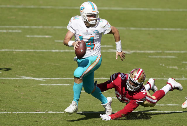 Dolphins quarterback Ryan Fitzpatrick avoids a tackle while looking to throw.