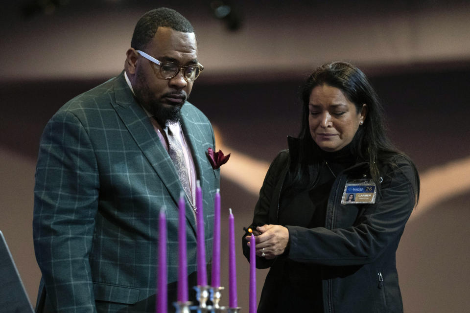 Hagins K. Conyers Jr., left, assists Carmen Kingston as she lights a candle for Fernando "Jesus" Chavez-Barron, 16, of Chesapeake, Va., during a prayer vigil held by the Chesapeake Coalition of Black Pastors at The Mount (Mount Lebanon Baptist Church) in Chesapeake, Va., Sunday, Nov. 27, 2022, for the six people killed, including Chavez-Barron, at a Walmart in Chesapeake, Va., when a manager opened fire with a handgun before an employee meeting Tuesday night. (AP Photo/Carolyn Kaster)