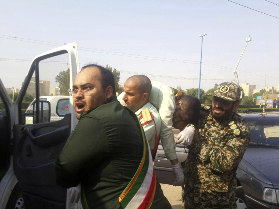 In this photo provided by the Iranian Students' News Agency, ISNA, Revolutionary Guard members carry a wounded comrade after a shooting during their parade marking the 38th anniversary of Iraq's 1980 invasion of Iran, in the southwestern city of Ahvaz, Iran, Saturday, Sept. 22, 2018. Gunmen attacked the military parade, killing at least eight members of the elite Revolutionary Guard and wounding 20 others, state media said. (AP Photo/ISNA, Shayan Haji Najaf)