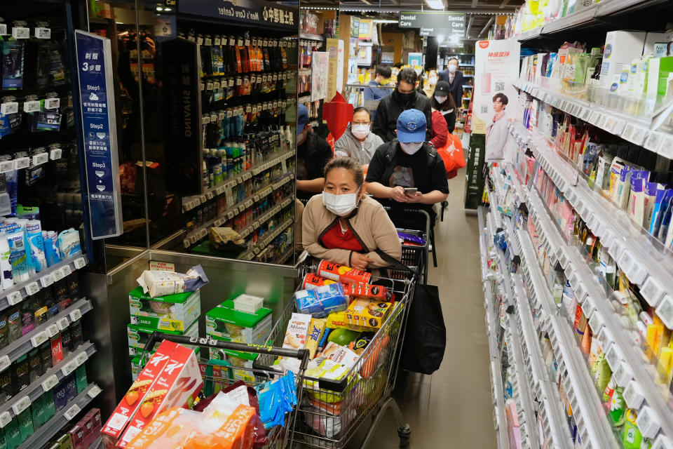 People wearing face masks queue up to pay as residents worry about a shortage of fresh food at a market in Hong Kong Monday, Feb. 28, 2022. Hong Kong on Monday reported a record-high 34,466 infections, with health authorities saying that a lockdown has not been ruled out as fatalities continued to climb. (AP Photo/Vincent Yu)