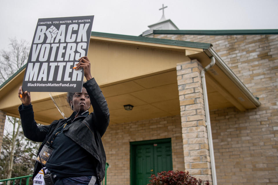 A woman about to join a march holds up a sign reading: Black Voters Matter.