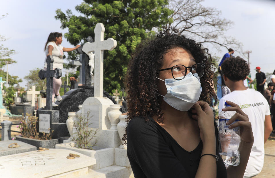A woman wears a mask against the spread of COVID-19 disease, as she attends a funeral at the Central cemetery of Managua, Nicaragua, Monday, May 11, 2020. President Daniel Ortega's government has stood out for its refusal to impose measures to halt the new coronavirus for more than two months since the disease was first diagnosed in Nicaragua. Now, doctors and family members of apparent victims say, the government has gone from denying the disease's presence in the country to actively trying to conceal its spread. (AP Photo/Alfredo Zuniga)