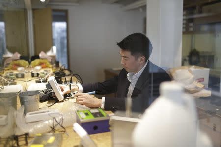 PureLiving's CEO Louie Cheng holds a device measuring air quality during an interview with Reuters in his office in Shanghai, December 21, 2015. REUTERS/Aly Song