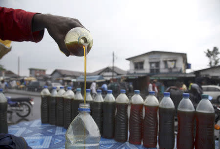 A Nigerian oil dealer pours gasoline into bottles at a roadside market in the commercial capital of Lagos in this October 31, 2008 file photo. REUTERS/Akintunde Akinleye/Files