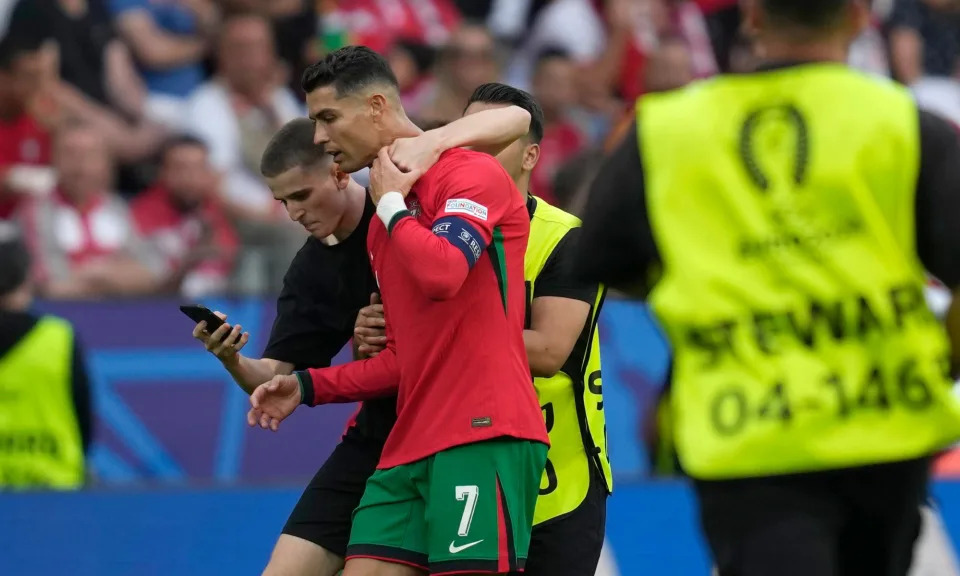 <span>One of several Cristiano Ronaldo-related pitch invaders tries to take a selfie with the <a class="link " href="https://sports.yahoo.com/soccer/teams/portugal/" data-i13n="sec:content-canvas;subsec:anchor_text;elm:context_link" data-ylk="slk:Portugal;sec:content-canvas;subsec:anchor_text;elm:context_link;itc:0">Portugal</a> captain in Dortmund.</span><span>Photograph: Darko Vojinović/AP</span>