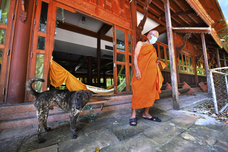 A Buddhist monk stands in front of a damage door after an explosion at King Kaeo Temple in Samut Prakan province, Thailand, Monday, July 5, 2021. A massive explosion at a factory on the outskirts of Bangkok early Monday shook an airport terminal serving Thailand's capital and prompted the evacuation of residents from the area. (AP Photo)