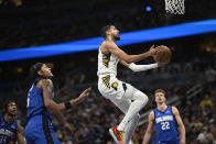 Indiana Pacers guard Tyrese Haliburton goes up for a shot as Orlando Magic center Wendell Carter Jr. (34), forward Paolo Banchero, second from left, and forward Franz Wagner (22) look on during the first half of an NBA basketball game, Sunday, March 10, 2024, in Orlando, Fla. (AP Photo/Phelan M. Ebenhack)