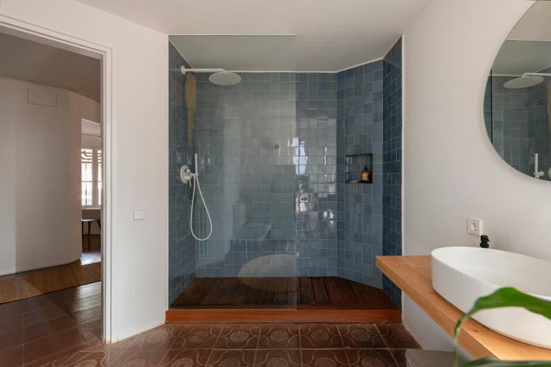 Blue tiled shower in bathroom.