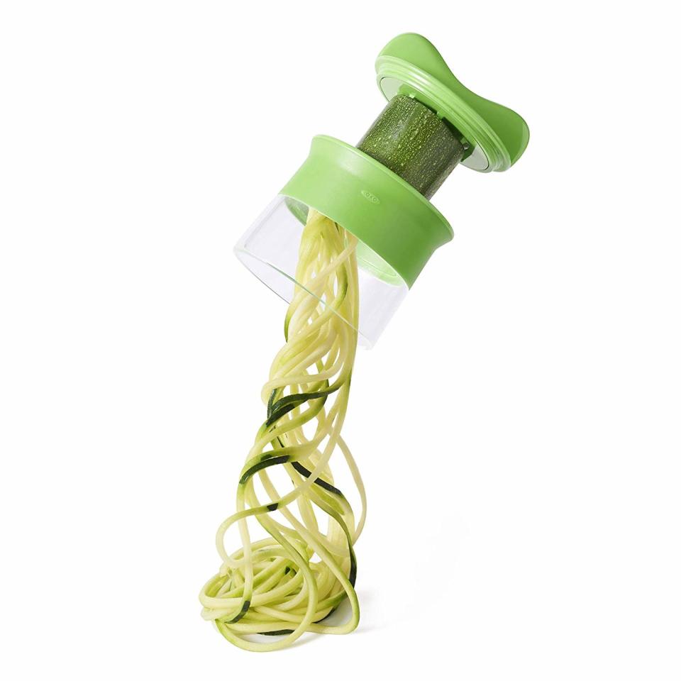 an oxo zucchini noodle maker making zucchini noodles on a white background