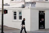 A pedestrian passes under for rent and for lease signs in San Francisco on Wednesday, Oct. 21, 2020. As the coronavirus pandemic transforms San Francisco's workplace, legions of tech workers have left, able to work remotely from anywhere. Families have fled for roomy suburban homes with backyards. The exodus has pushed rents in the prohibitively expensive city to their lowest in years. (AP Photo/Noah Berger)