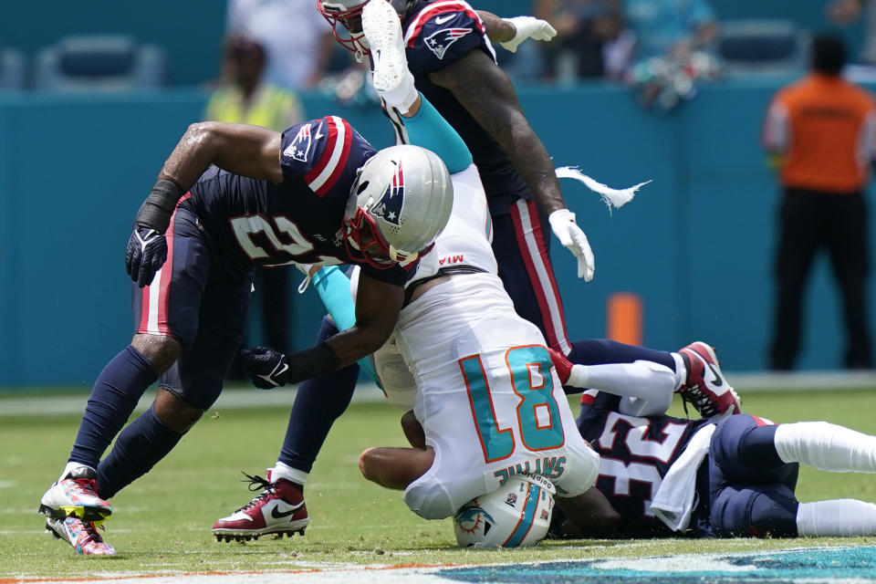 New England Patriots safety Adrian Phillips (21) and Devin McCourty (32) up end Miami Dolphins tight end Durham Smythe (81) during the first half of an NFL football game, Sunday, Sept. 11, 2022, in Miami Gardens, Fla. (AP Photo/Lynne Sladky)
