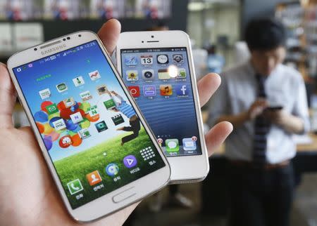 Samsung Electronics' Galaxy S4 (L) and Apple's iPhone 5 are seen in this picture illustration taken in Seoul, South Korea May 13, 2013. REUTERS/Kim Hong-Ji/File Photo