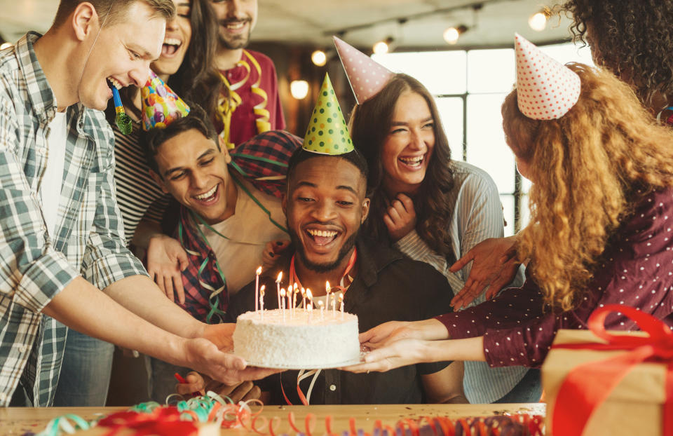 birthday cake being placed in front of a person at a party