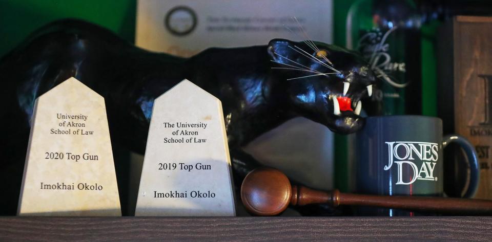 Imokhai Okolo proudly displays awards from his success in the 2019 and 2020 Baylor Law Top Gun National Mock Trial competitions next to a gavel and Jones Day coffee cup.