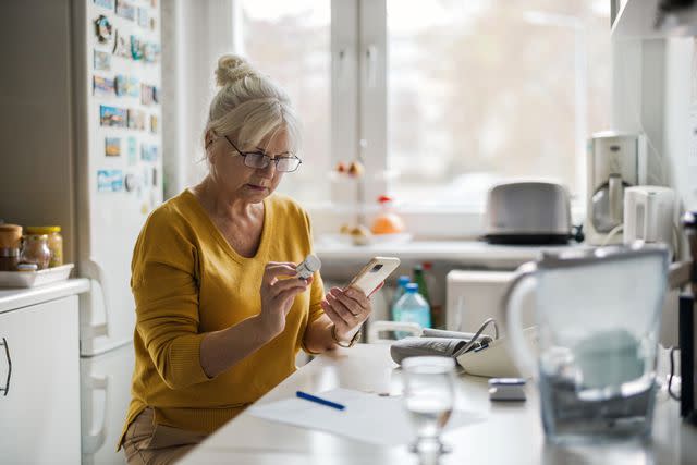 <p>PIKSEL / Getty Images</p> Older female checking prescription with cellphone