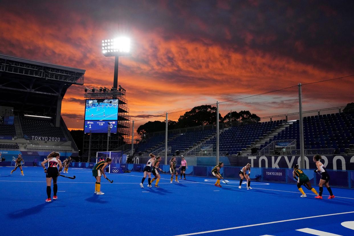 The setting sun lights up the sky as South Africa and Great Britain compete during a women's field hockey match at the 2020 Summer Olympics, Monday, July 26, 2021, in Tokyo, Japan.