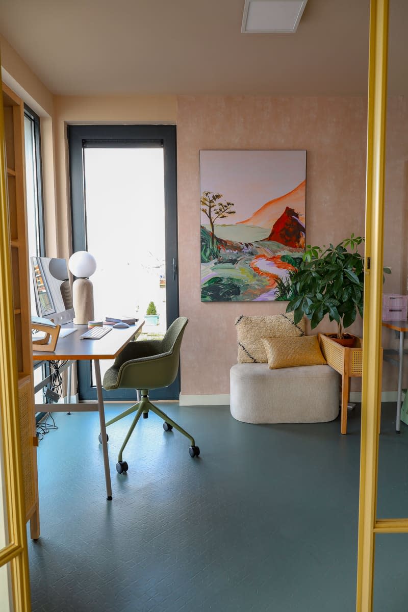 Office with pastel wall and floor seen from hallway.