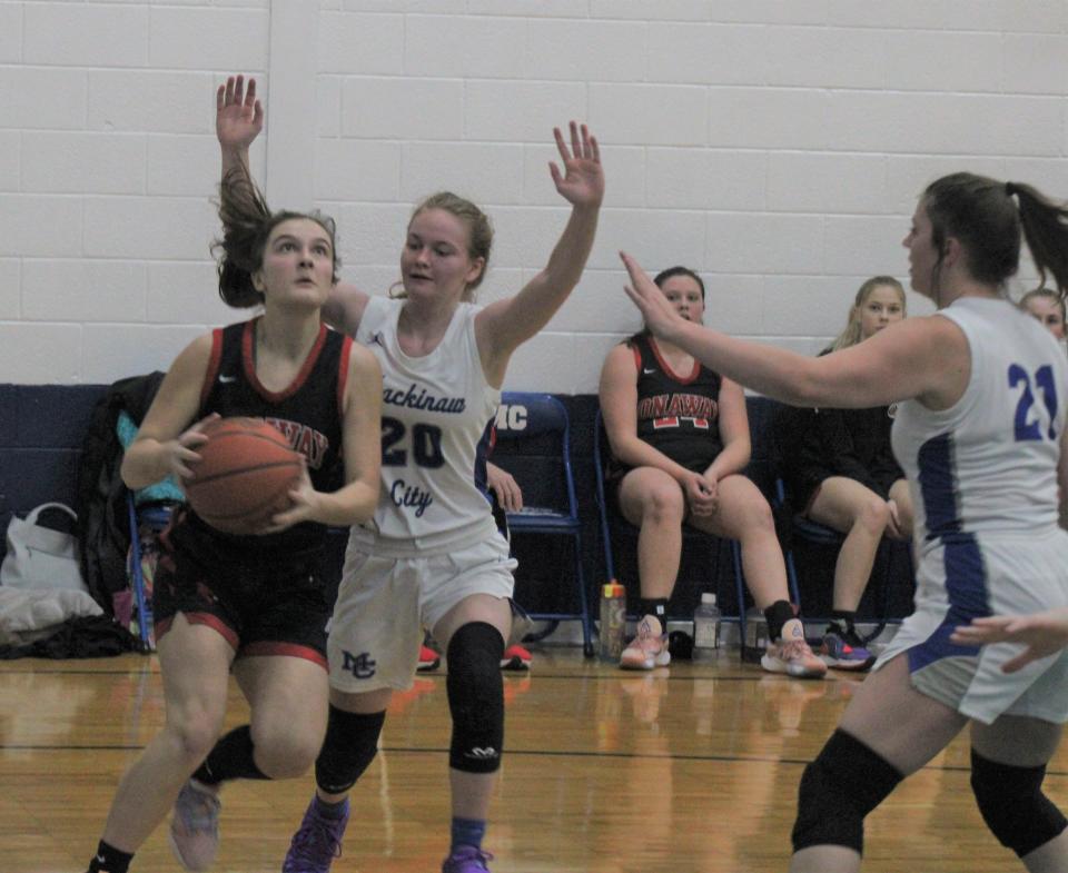 Onaway sophomore Kailyn George (left) looks to get to the basket while Mackinaw City's Gracie Beauchamp (20) and Julia Sullivan (21) defend during the second half.