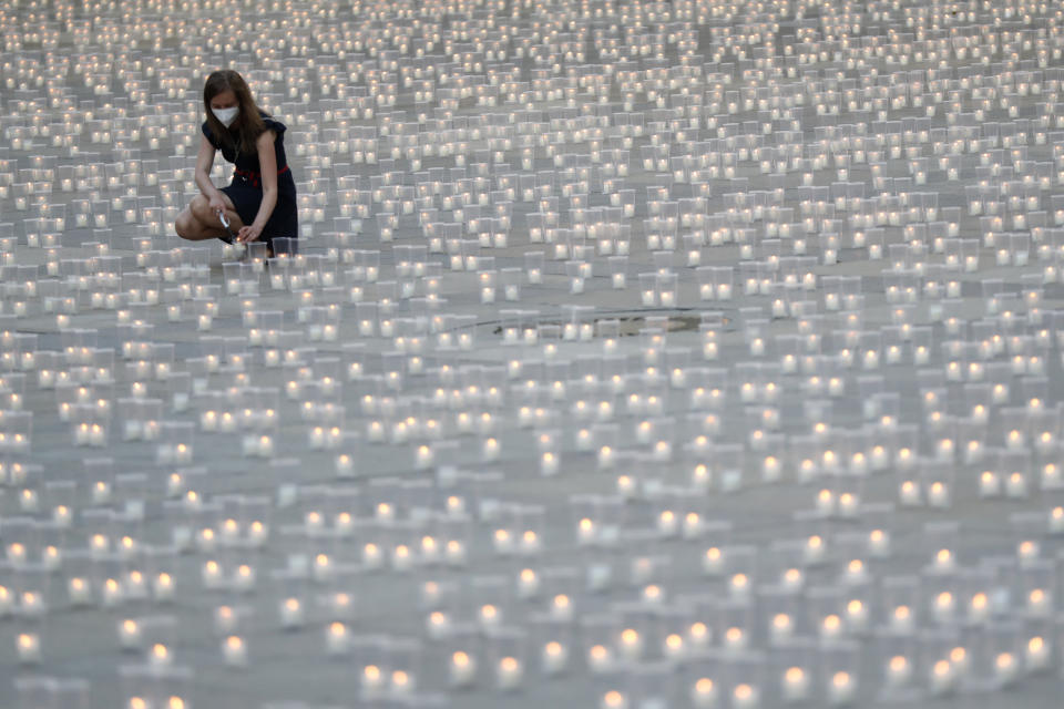 Woman lights a candle to commemorate victims of the COVD-19 pandemic at the Prague Castle in Prague, Czech Republic, Monday, May 10, 2021. The Czech Republic is massively relaxing its coronavirus restrictions as the hard-hit nation pays respect to nearly 30,000 dead. (AP Photo/Petr David Josek)