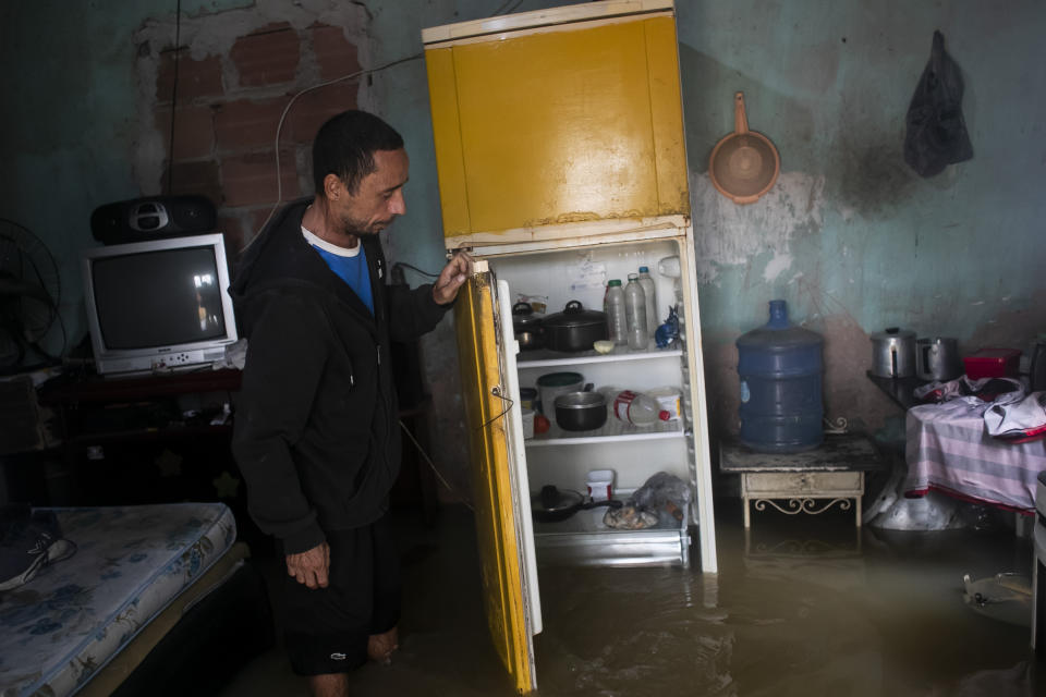 Nicelio Goncalves abre la nevera en su casa inundada por las fuertes lluvias caídas en Duque de Caxias, Brasil, el 24 de marzo de 2024. (AP Foto/Bruna Prado)