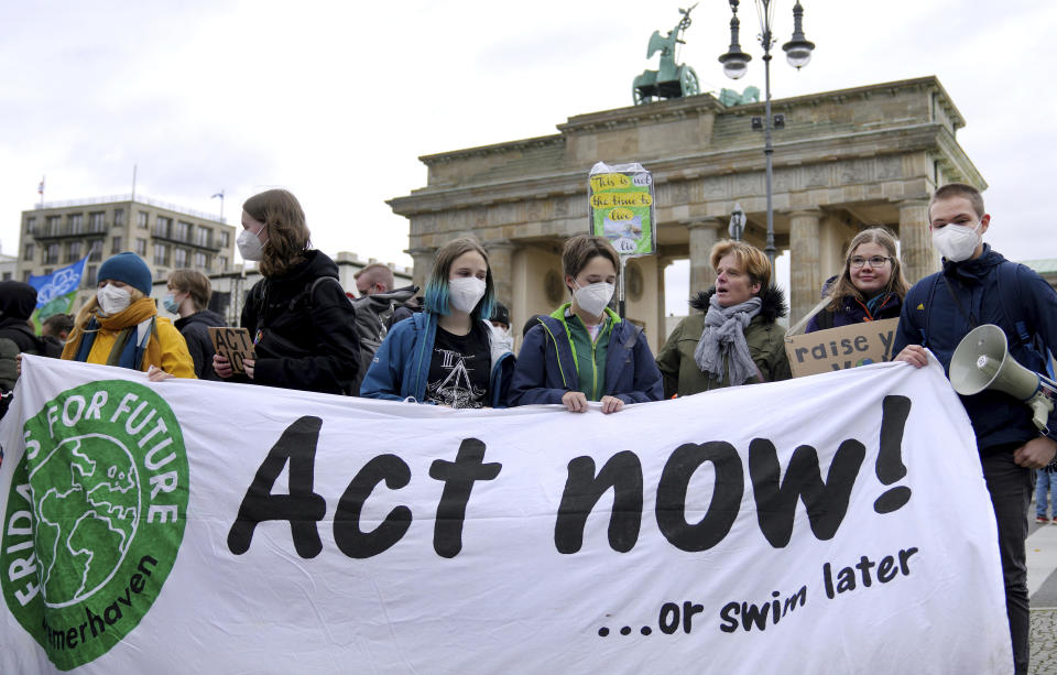 People stay in front of the Brandenburg Gate as they take part in a 'Fridays For Future' climate protest rally in Berlin, Germany, Friday, Oct. 22, 2021. (AP Photo/Michael Sohn)