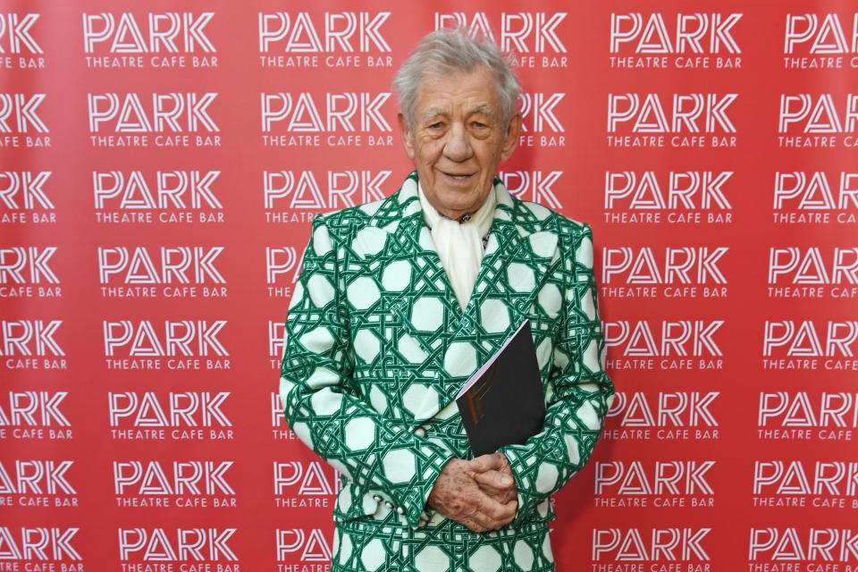 Sir Ian McKellen, smiling as he wears a blazer with a bold green pattern and carries a programme book, attends the Park Theatre 10th Anniversary party