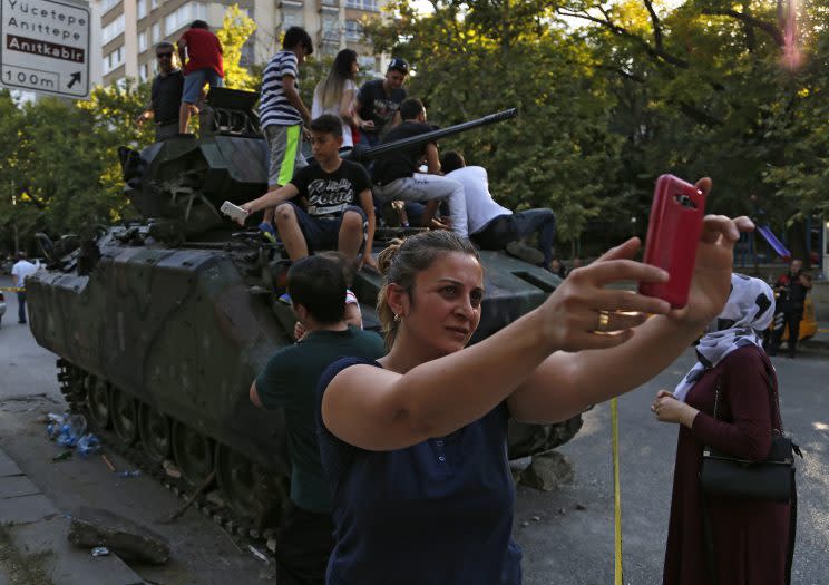 Taking selfies at a damaged armored personnel carrier that was attacked by protesters near the Turkish military headquarters in Ankara. (AP Photo/Hussein Malla)