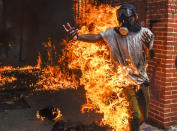 <p>A demonstrator catches fire, after the gas tank of a police motorbike exploded, during clashes in a protest against Venezuelan President Nicolas Maduro, in Caracas on May 3, 2017. (Photo: Juan Barreto/AFP/Getty Images) </p>