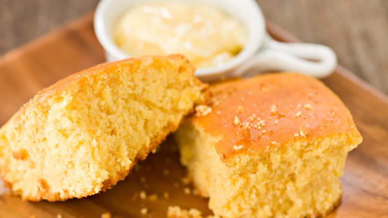 sliced cornbread on wood platter with butter