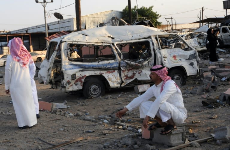 Saudis wait next to wreckages at a market for vehicles on August 27, 2016 in the Saudi border city of Najran, a week after it was struck by a rocket fired from Yemen