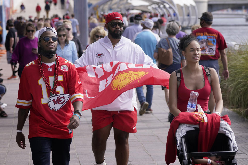 People wear masks as they walk down a sidewalk near Super Bowl 55 activities Friday, Feb. 5, 2021, in Tampa, Fla. The city is hosting Sunday's Super Bowl football game between the Tampa Bay Buccaneers and the Kansas City Chiefs. (AP Photo/Charlie Riedel)
