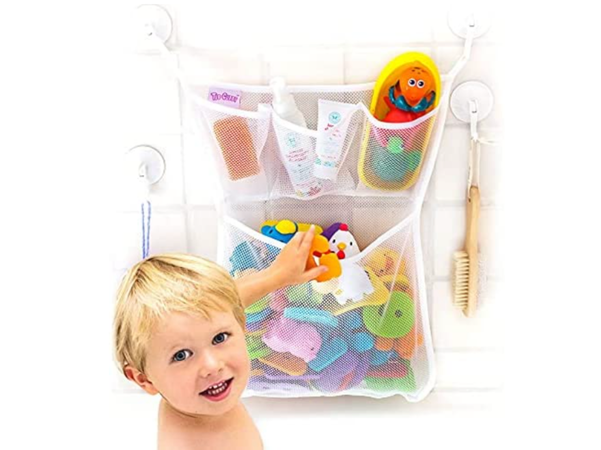 Toddler putting a toy into a net pocket for storing toys on a tile wall