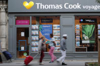 People walk past a Thomas Cook travel shop in Paris, Monday, Sept. 23, 2019. British tour company Thomas Cook collapsed early Monday after failing to secure emergency funding, leaving tens of thousands of vacationers stranded abroad. (AP Photo/Francois Mori)