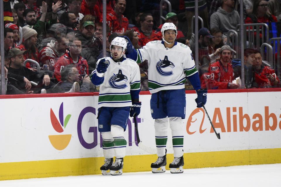 Vancouver Canucks right wing Conor Garland, left, celebrates after his goal with center Dakota Joshua, right, during the first period of an NHL hockey game against the Washington Capitals, Sunday, Feb. 11, 2024, in Washington. (AP Photo/Nick Wass)