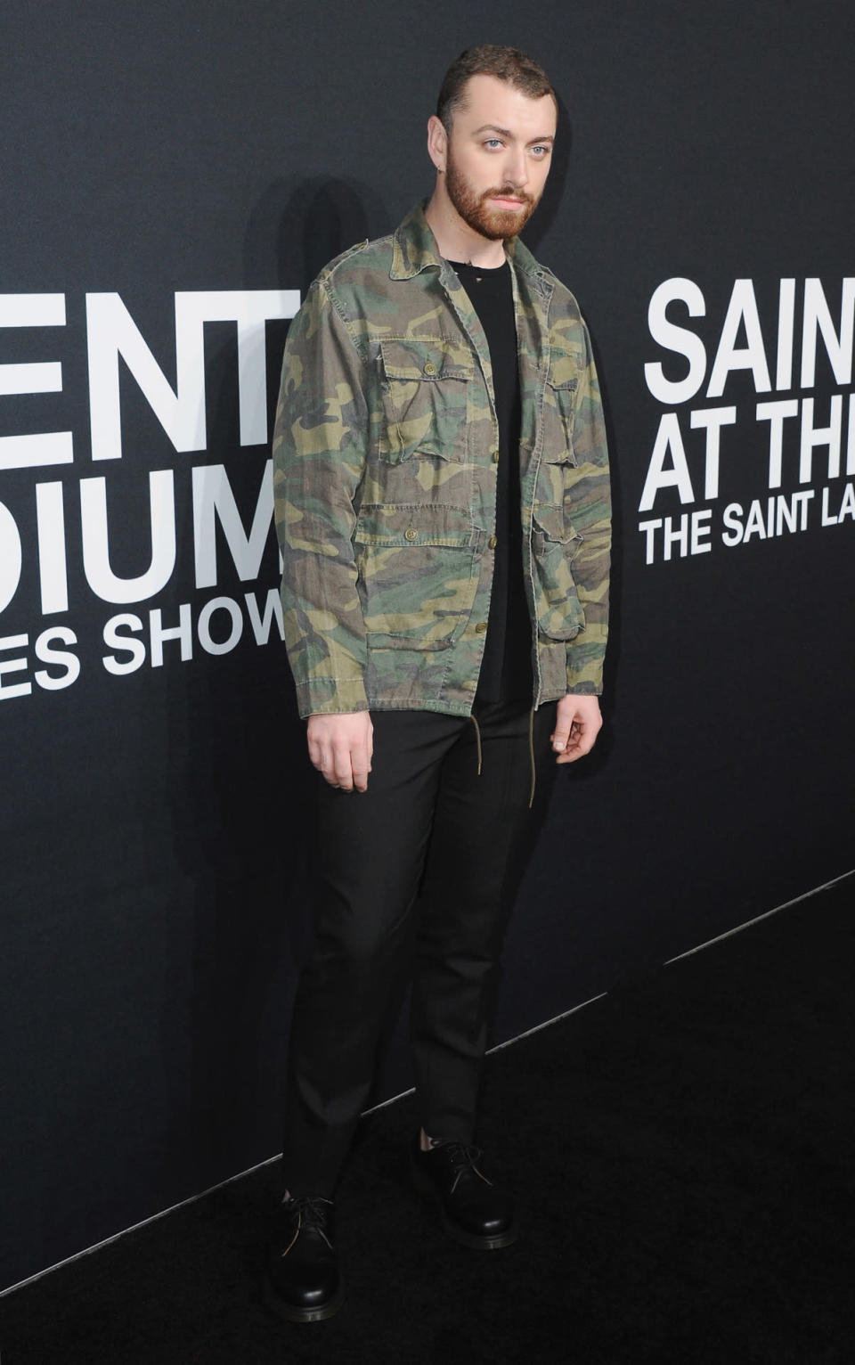 Sam Smith in a camouflage blazer and black jeans.  