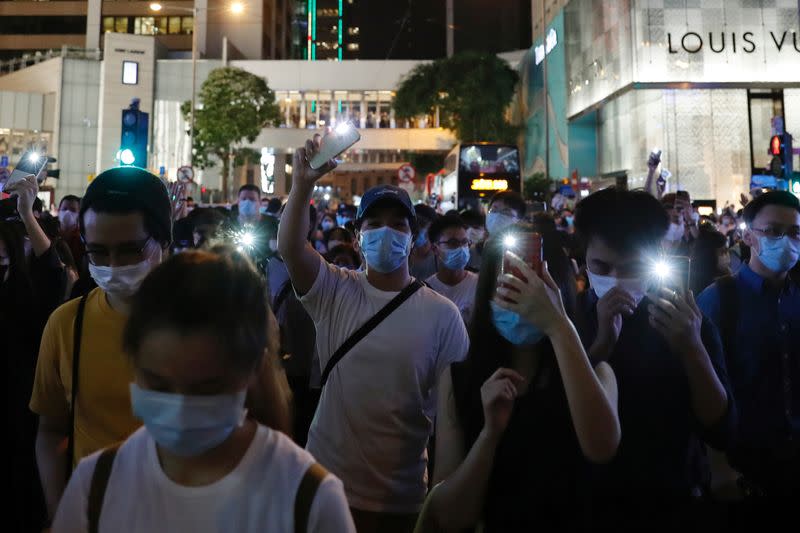 Pro-democracy demonstrators march holding their phones with flashlights on during a protest to mark the first anniversary of a mass rally against the now-withdrawn extradition bill, in Hong Kong