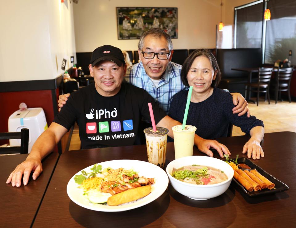 From left, Pho Town 6 owner James Pham, left, his sister Hanna Nguyen, right, the operations manager of Pho Town 6, and Hanna's husband Van Nguyen, center, show off some of the Brockton restaurant's authentic Vietnamese dishes on Wednesday, Sept. 21, 2022.