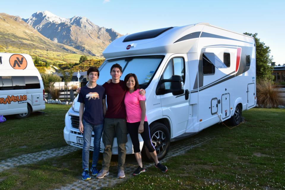 This Dec. 23, 2019, photo shows the Foster family, from left, Miles, 16, Jacob, 17, and Mio, posing in front of their rented camper van at Mrs. Woolly’s Campground in Glenorchy, New Zealand. Touring in a camper van is a popular way for tourists to see the country. (Malcolm Foster via AP)
