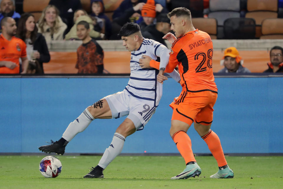 Sporting Kansas City forward Alan Pulido (9) blocks out Houston Dynamo defender Erik Sviatchenko during the first half of an MLS playoff soccer match, Sunday, Nov. 26, 2023, in Houston. (AP Photo/Michael Wyke)