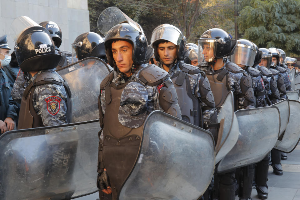 Police guard during a protest against an agreement to halt fighting over the Nagorno-Karabakh region, in front of the government building in Yerevan, Armenia, Wednesday, Nov. 11, 2020. Thousands of people flooded the streets of Yerevan once again on Wednesday, protesting an agreement between Armenia and Azerbaijan to halt the fighting over Nagorno-Karabakh, which calls for deployment of nearly 2,000 Russian peacekeepers and territorial concessions. Protesters clashed with police, and scores have been detained. (AP Photo/Dmitri Lovetsky)