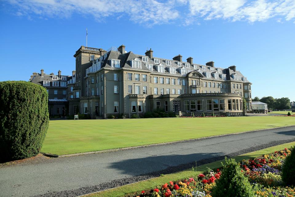 An exterior view of an old hotel in Scotland with white window panes and a Scottish flap waving from the top.