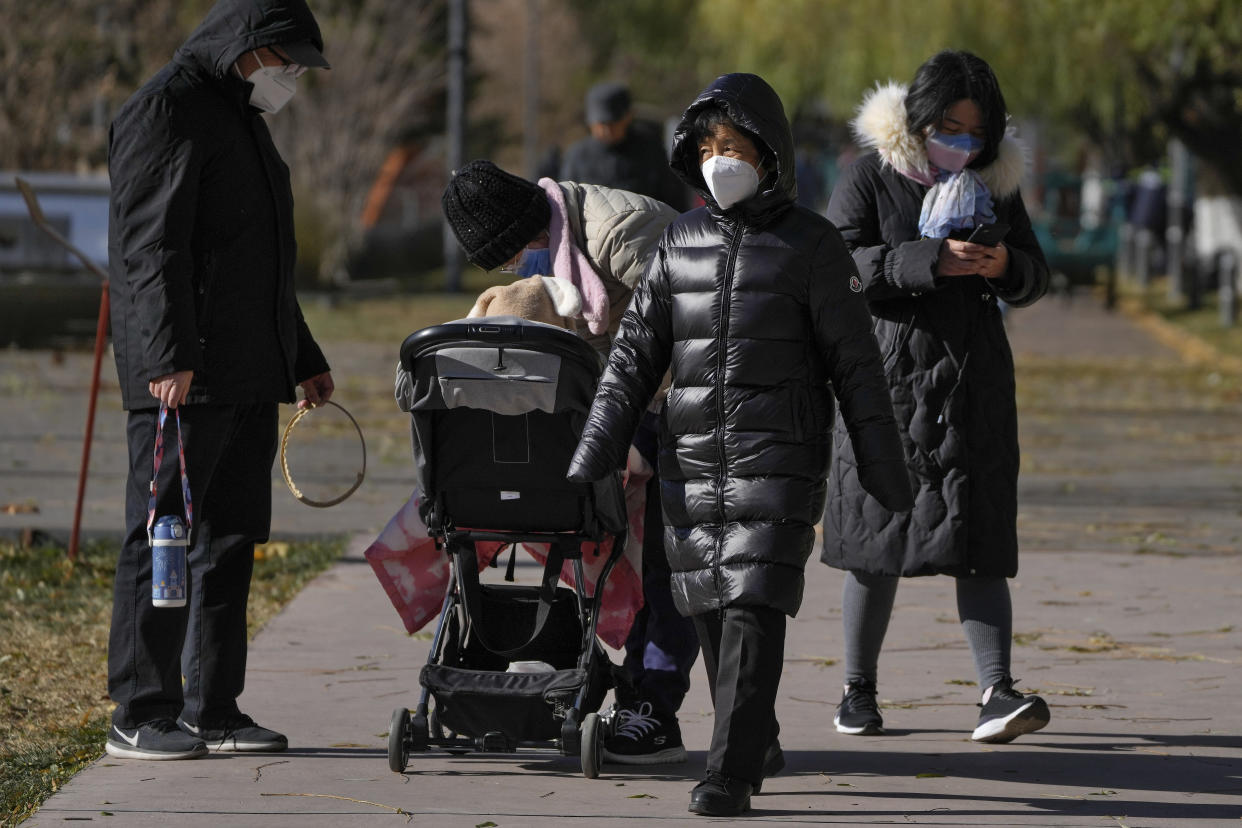 Residents wearing a face masks walk through a riverbank near the site of last weekend's protest in Beijing, Wednesday, Nov. 30, 2022. China's ruling Communist Party has vowed to "resolutely crack down on infiltration and sabotage activities by hostile forces," following the largest street demonstrations in decades staged by citizens fed up with strict anti-virus restrictions. (AP Photo/Andy Wong)