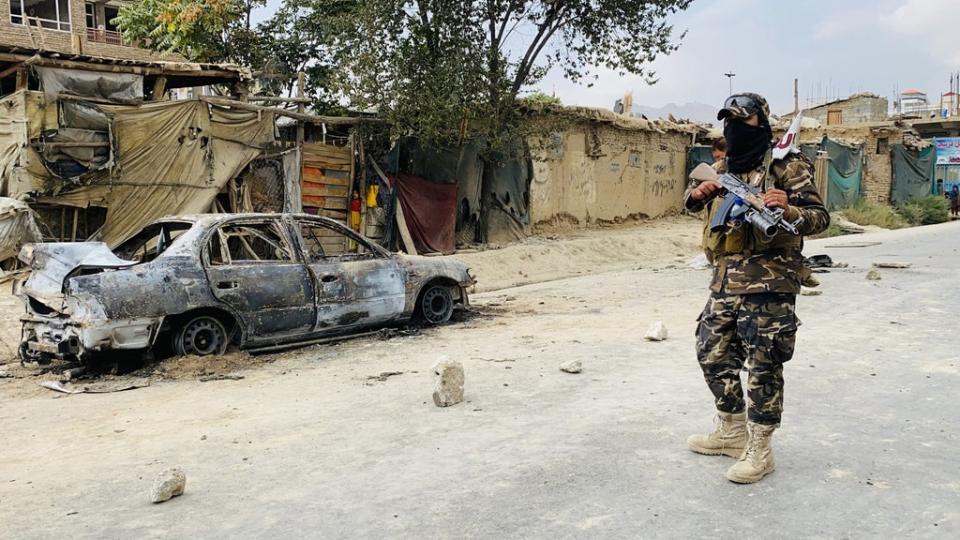 A member of the Taliban stands guard near a vehicle that was used to fire rockets at the Hamid Karzai airport in Kabul (EPA)