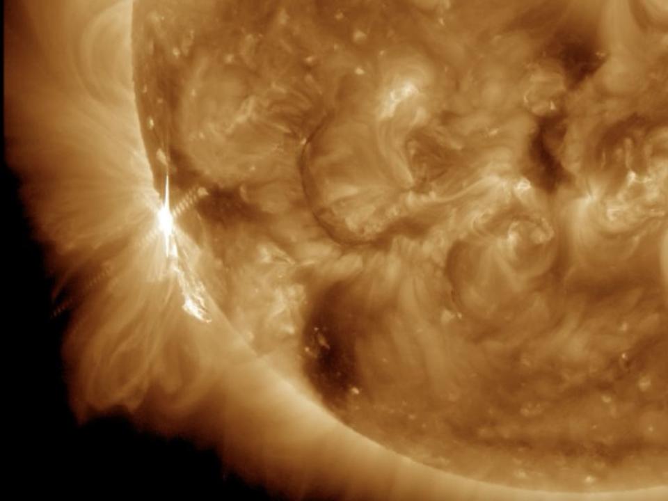A flash of light appears where the solar flare is released on the left side of the sun.