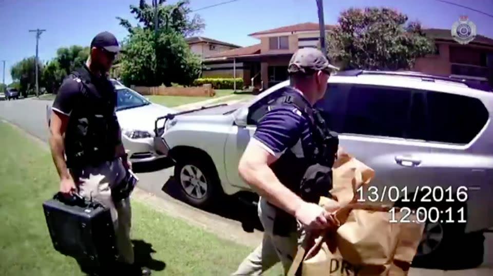 Officers remove evidence from the property, believed to be occupied by a Rebels bikie member. Photo: QPS Media