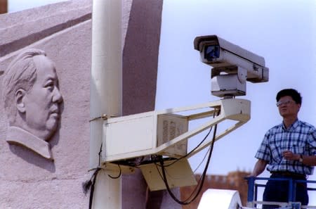 FILE PHOTO: A state electrician checks a remote-control surveillance camera used to monitor Tiananmen Square and the Monument to the People's Heroes in Beijing